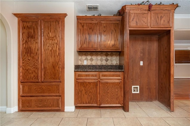 kitchen with decorative backsplash, light tile patterned floors, and dark stone counters