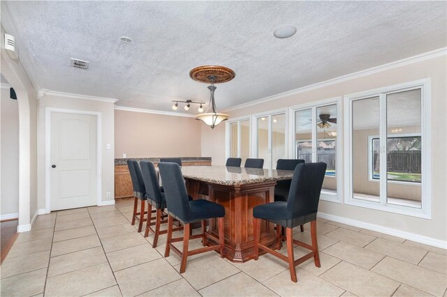 dining space featuring a textured ceiling, light tile patterned floors, and crown molding