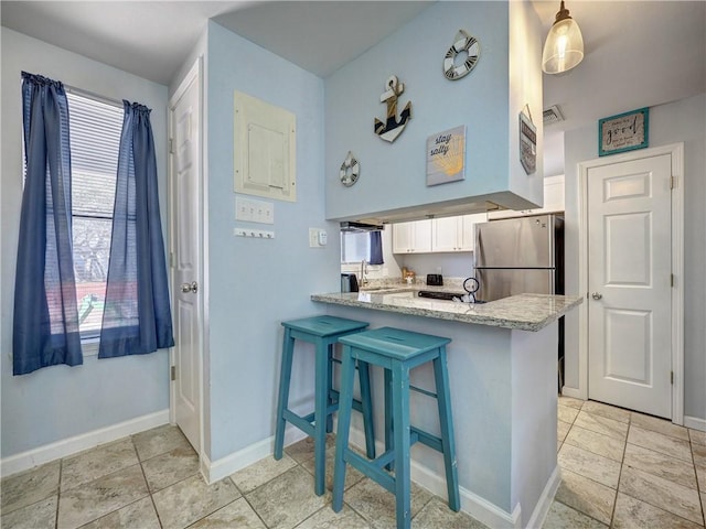 kitchen with decorative light fixtures, white cabinets, a breakfast bar, and kitchen peninsula