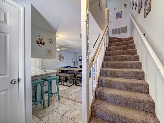 staircase with tile patterned floors and ceiling fan