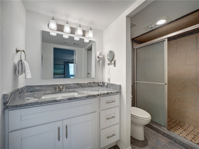 bathroom featuring a shower with door, tile patterned flooring, a textured ceiling, vanity, and toilet