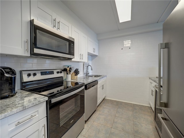 kitchen with white cabinets, light tile patterned floors, sink, and appliances with stainless steel finishes