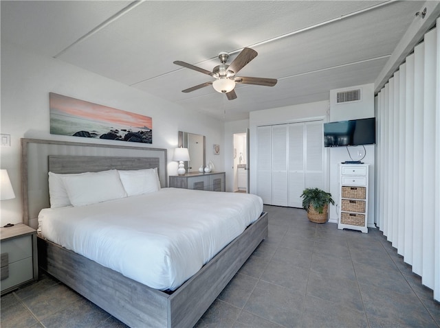 bedroom featuring ceiling fan, a closet, and dark tile patterned floors