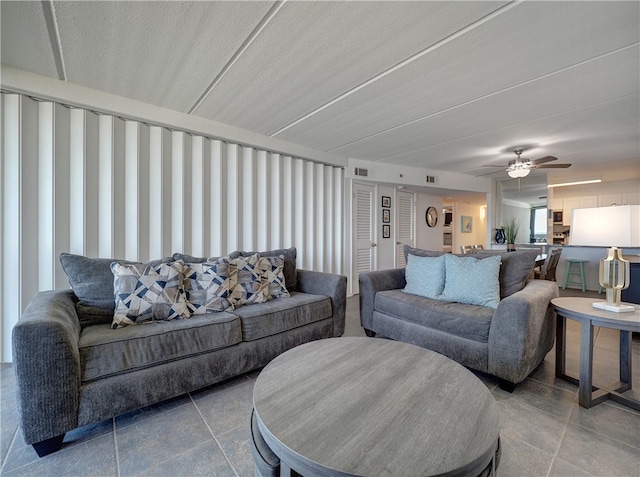 living room with ceiling fan and a textured ceiling