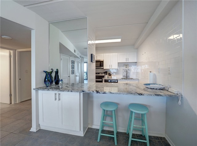 kitchen featuring backsplash, white cabinetry, appliances with stainless steel finishes, and light stone counters