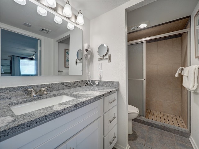 bathroom featuring vanity, a shower with door, tile patterned flooring, and toilet