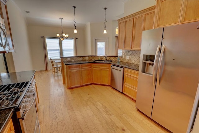 kitchen featuring stainless steel appliances, a sink, a chandelier, light wood-type flooring, and backsplash