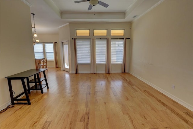 spare room featuring ceiling fan, a tray ceiling, crown molding, light wood-type flooring, and baseboards