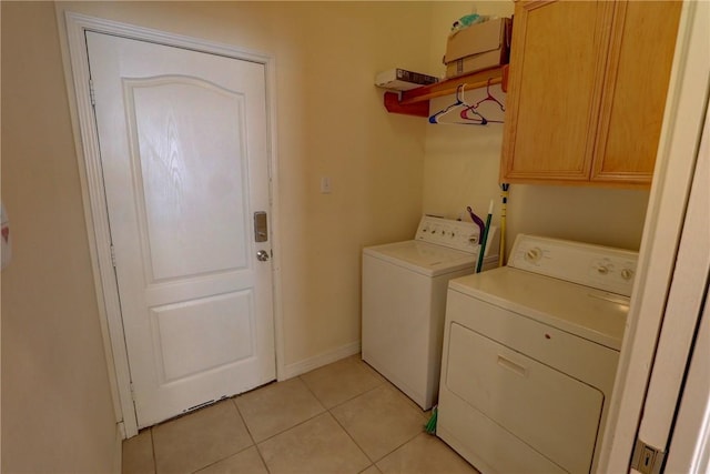 clothes washing area featuring cabinet space, washer and dryer, light tile patterned floors, and baseboards