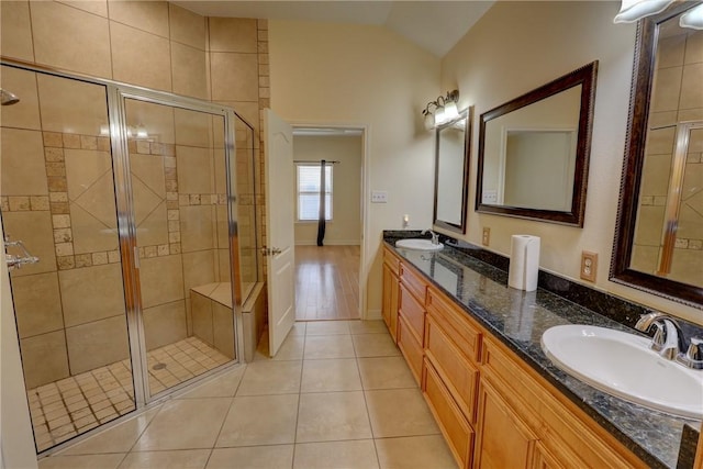 bathroom featuring lofted ceiling, a shower stall, tile patterned flooring, and double vanity