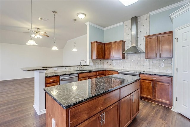 kitchen with wall chimney range hood, sink, a kitchen island, stainless steel dishwasher, and dark stone counters