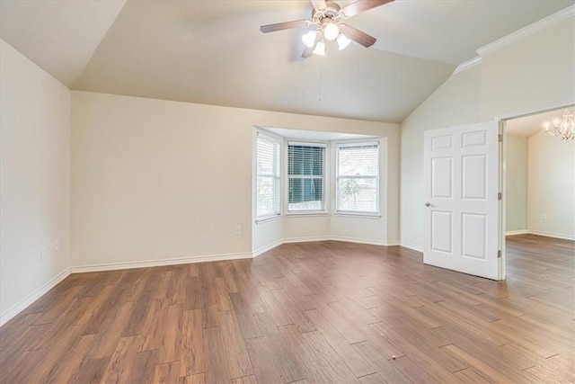 spare room with hardwood / wood-style floors, ceiling fan with notable chandelier, and vaulted ceiling