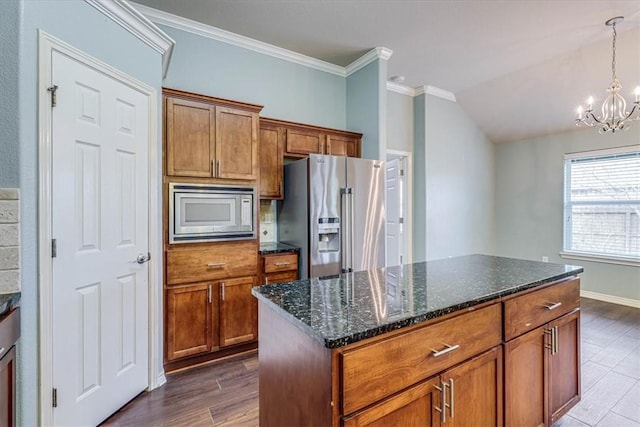 kitchen featuring a chandelier, a center island, hanging light fixtures, dark stone countertops, and appliances with stainless steel finishes