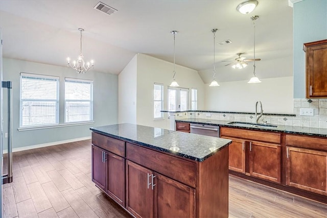 kitchen with pendant lighting, sink, stainless steel dishwasher, and dark stone counters