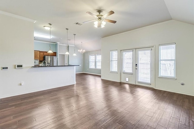 unfurnished living room with lofted ceiling, ceiling fan with notable chandelier, dark wood-type flooring, and ornamental molding