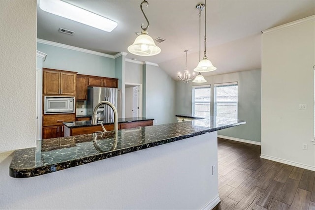 kitchen with appliances with stainless steel finishes, dark hardwood / wood-style floors, pendant lighting, dark stone counters, and crown molding