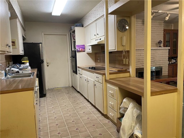 5406 Fresno Dr, Corpus Christi, TX 78411 - kitchen with under cabinet range hood, a sink, black appliances, wooden counters, and rail lighting