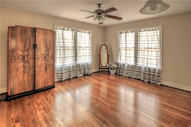 unfurnished bedroom with ceiling fan, wood-type flooring, multiple windows, and ornamental molding