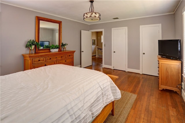 bedroom featuring dark wood-type flooring, an inviting chandelier, and crown molding