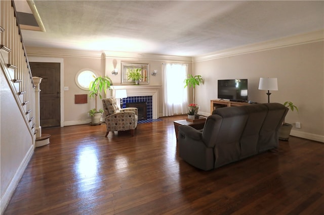 living room with ornamental molding, a tiled fireplace, and dark hardwood / wood-style floors