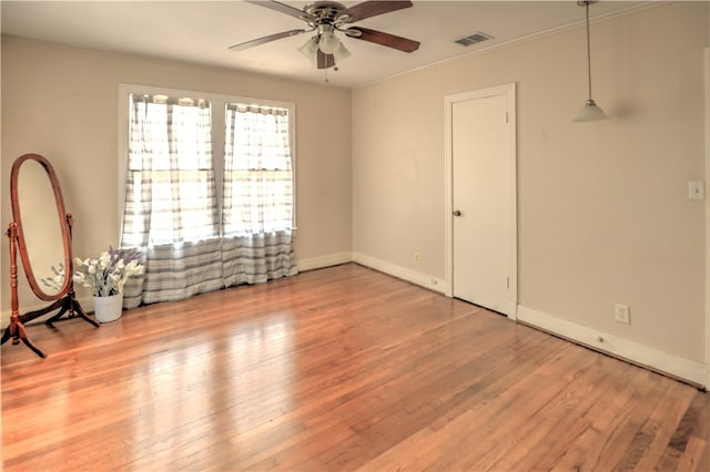 empty room with ornamental molding, hardwood / wood-style floors, and ceiling fan