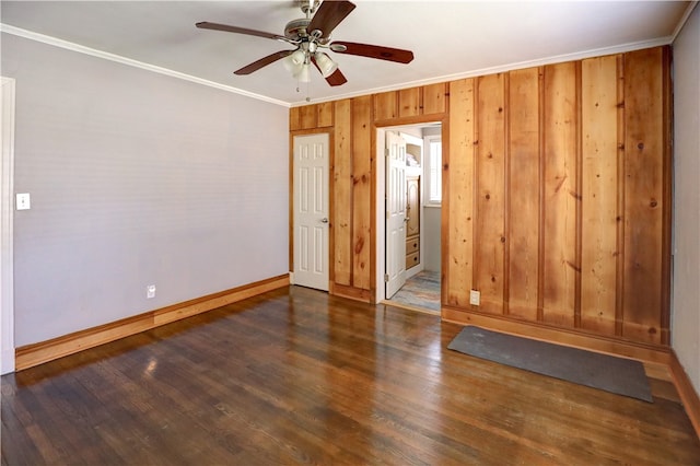 unfurnished room with dark hardwood / wood-style flooring, wood walls, ceiling fan, and crown molding