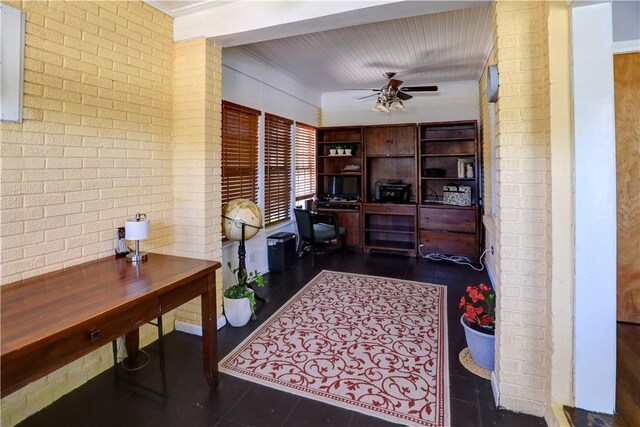 office space with brick wall, dark tile patterned floors, and ceiling fan