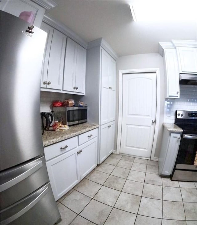 kitchen featuring range hood, white cabinetry, backsplash, light tile patterned floors, and stainless steel appliances