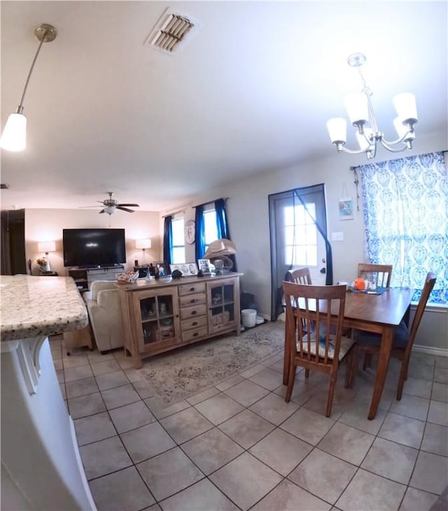 tiled dining area featuring plenty of natural light and ceiling fan with notable chandelier