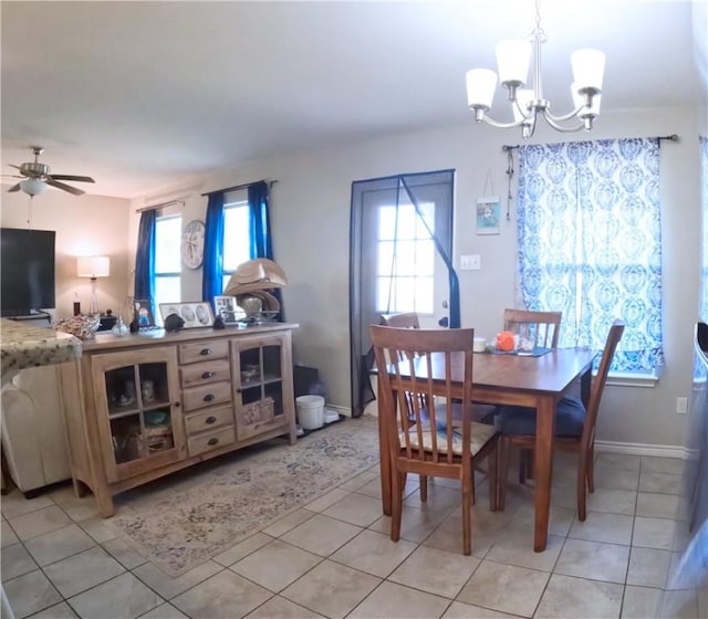 tiled dining space featuring plenty of natural light and ceiling fan with notable chandelier