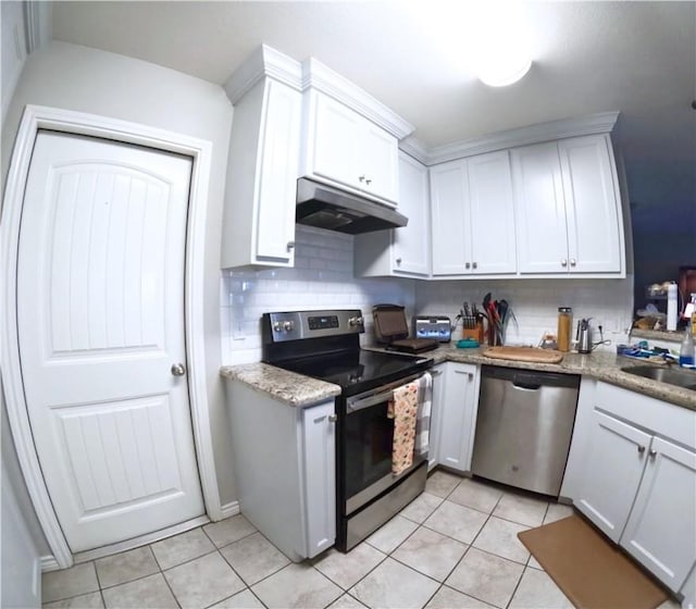 kitchen featuring stainless steel appliances, light tile patterned floors, white cabinets, and backsplash