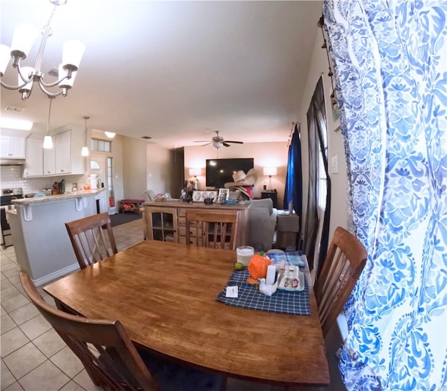 tiled dining area with ceiling fan with notable chandelier