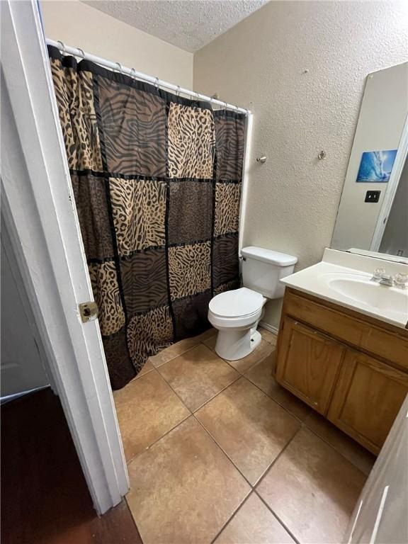 bathroom with a textured ceiling, vanity, toilet, and tile patterned floors