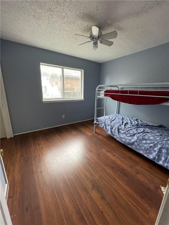 unfurnished bedroom featuring ceiling fan, dark hardwood / wood-style floors, and a textured ceiling