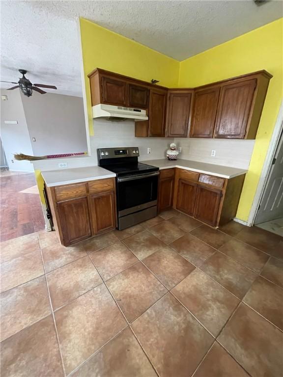 kitchen with kitchen peninsula, tile patterned floors, a textured ceiling, black range with electric cooktop, and ceiling fan