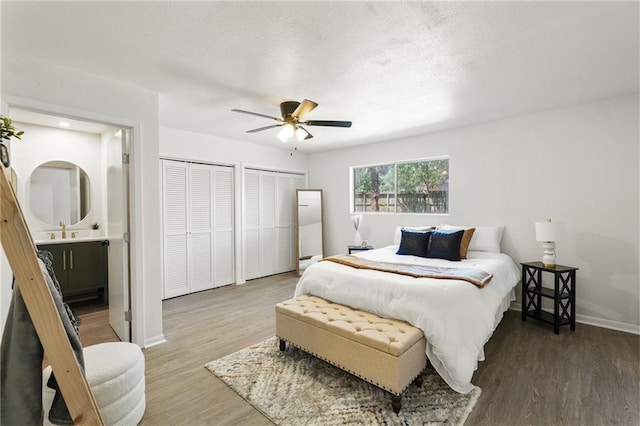 11029 Stonewall Blvd, Corpus Christi, TX 78410 - bedroom featuring two closets, wood finished floors, ensuite bath, a ceiling fan, and a textured ceiling