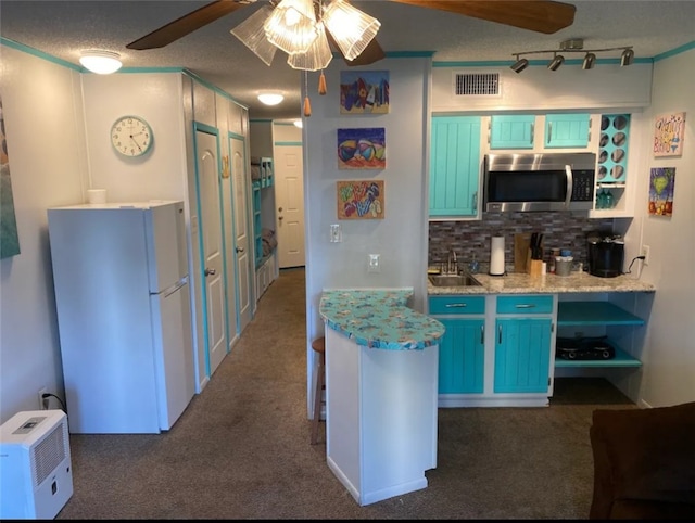 kitchen with decorative backsplash, blue cabinets, white refrigerator, and dark carpet