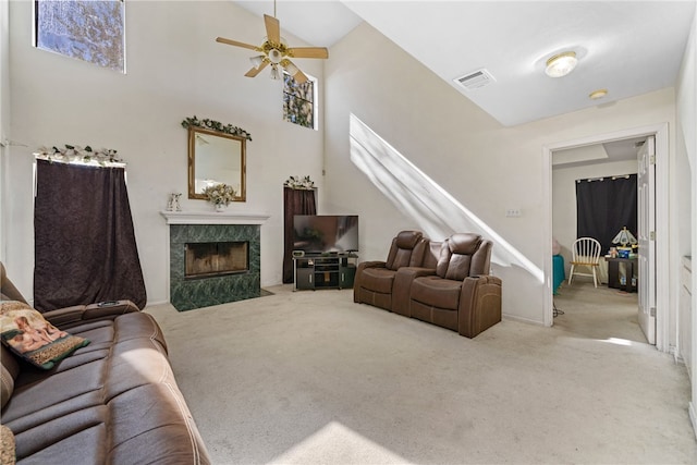 living room with a fireplace, a towering ceiling, light colored carpet, and ceiling fan