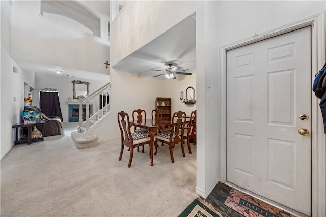 carpeted dining room featuring ceiling fan and a high ceiling