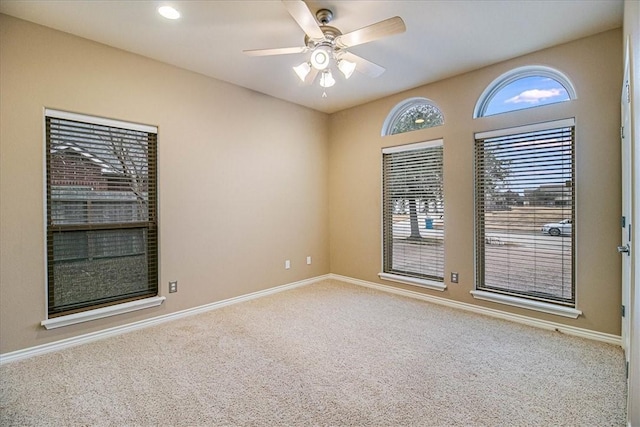 carpeted empty room with ceiling fan and a wealth of natural light