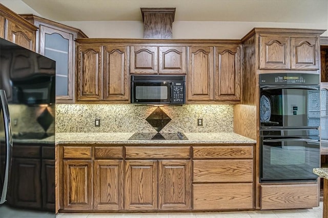 kitchen with tasteful backsplash, light stone counters, and black appliances