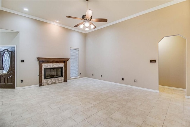 unfurnished living room with a tiled fireplace, crown molding, light tile patterned floors, and ceiling fan