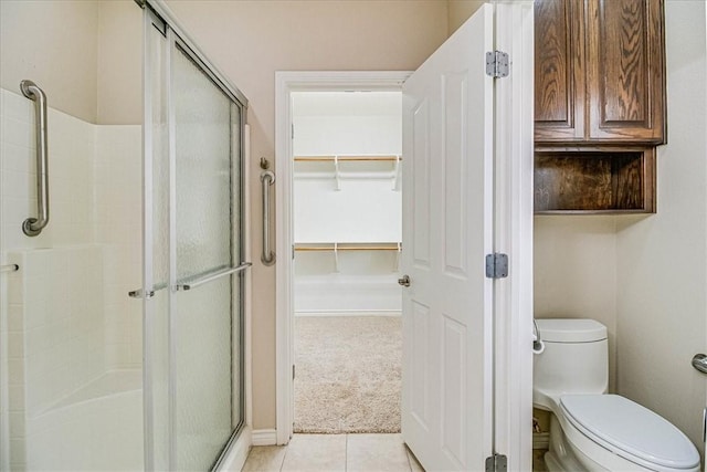 bathroom featuring tile patterned flooring, toilet, and walk in shower