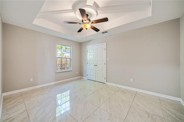 spare room featuring visible vents, baseboards, a ceiling fan, and a raised ceiling