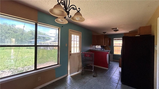 2993 Todd Cir, Ingleside, TX 78362 - kitchen with freestanding refrigerator, a textured ceiling, healthy amount of natural light, dark tile patterned floors, and baseboards