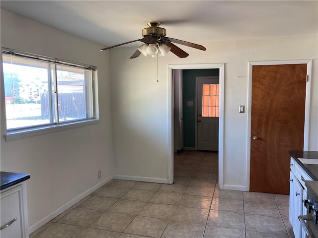 interior space featuring a ceiling fan, baseboards, and light tile patterned floors