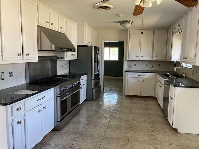 kitchen featuring a sink, dark countertops, under cabinet range hood, a ceiling fan, and appliances with stainless steel finishes