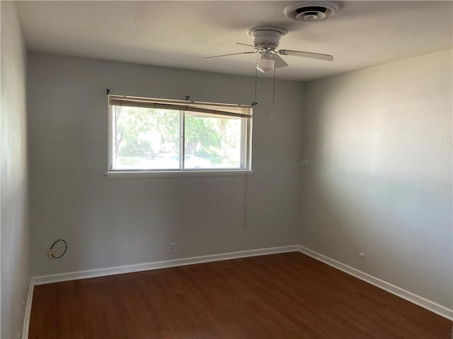 empty room with ceiling fan, visible vents, dark wood-style floors, and baseboards