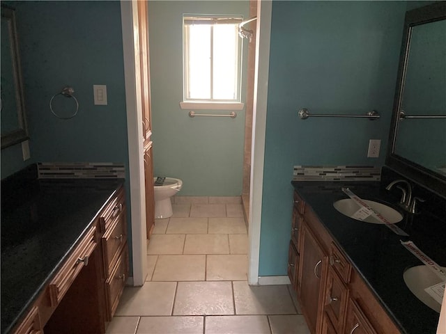 full bathroom featuring baseboards, double vanity, tile patterned floors, and a sink