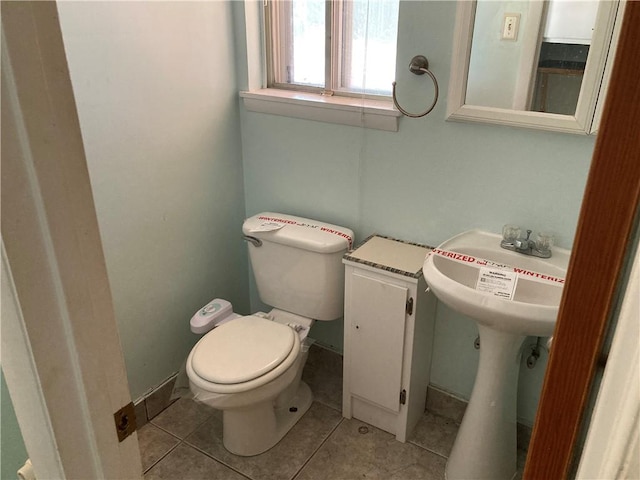 half bath with a sink, tile patterned floors, and toilet